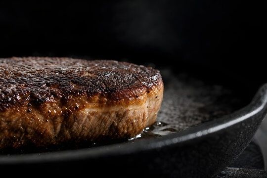 Närbild av en gyllenbrun, hårt stekt köttbit i en gjutjärnspanna
